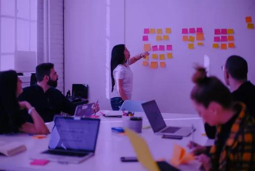 People in a brainstorm, looking at post-its on a wall.