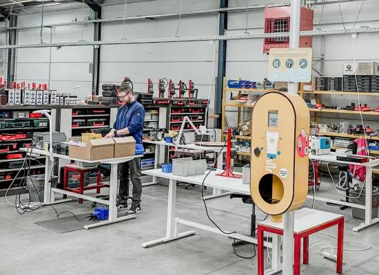 A technician works in a workshop assembling a SMOTspot solar cream dispenser.