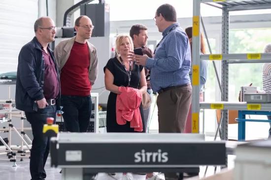  Un expert Sirris explique la stratégie de production à un groupe de visiteurs dans le laboratoire Sirris de Facthory à Genk, avec un AMR au premier plan.
