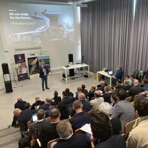 Man standing in front of an audience that is listening to his talk at a seminar. 